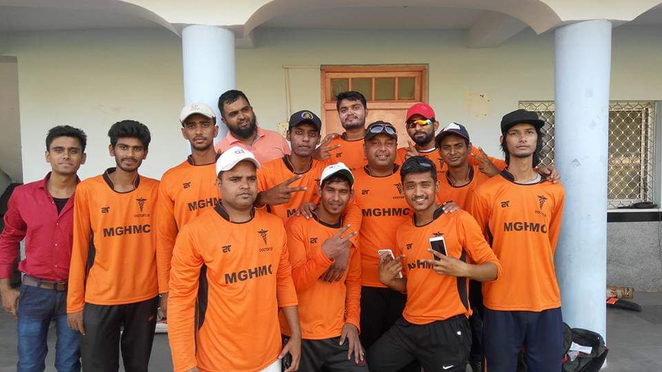 Cricket team of Mahatma Gandhi Homoeopathic Medical College in their orange jersey.